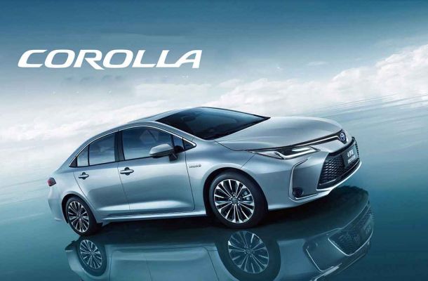 Silver Toyota Corolla with the word "COROLLA" above, set against a blue sky and reflective surface.