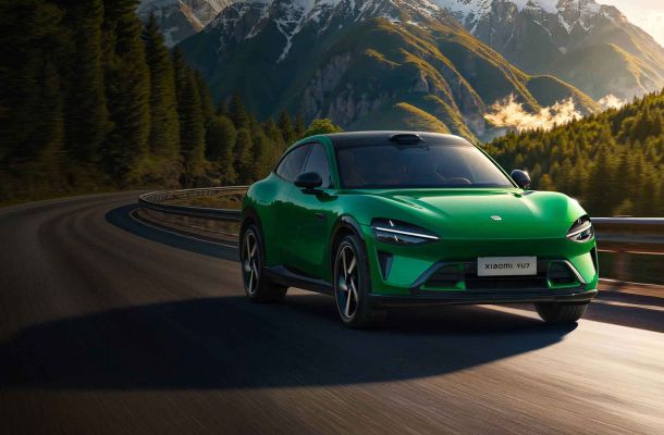 A green Xiaomi YU7 car driving on a winding road in a mountainous area.