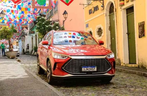 Red BYD car parked on a cobblestone street decorated with colorful flags.