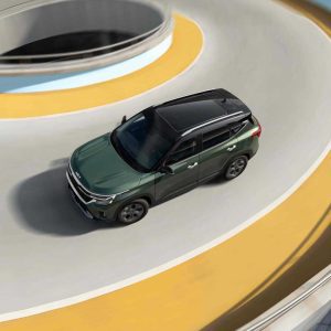 KIA Seltos 2023 1.5L CVT Premium Edition gallery6 A dark green Kia SUV driving on a curvy road.
