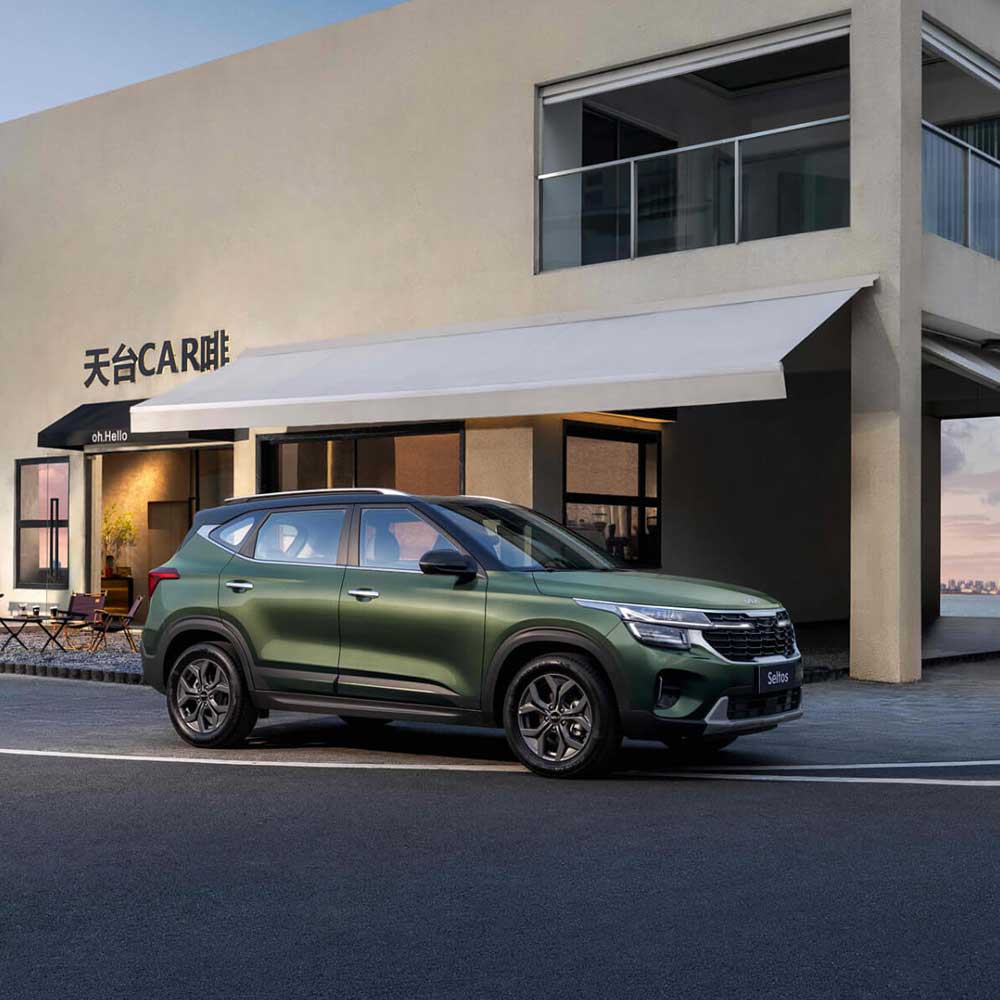 KIA Seltos 2023 1.5L CVT Premium Edition gallery7 A green Kia Seltos SUV parked in front of a building with "天台 CAR 啡" signage.