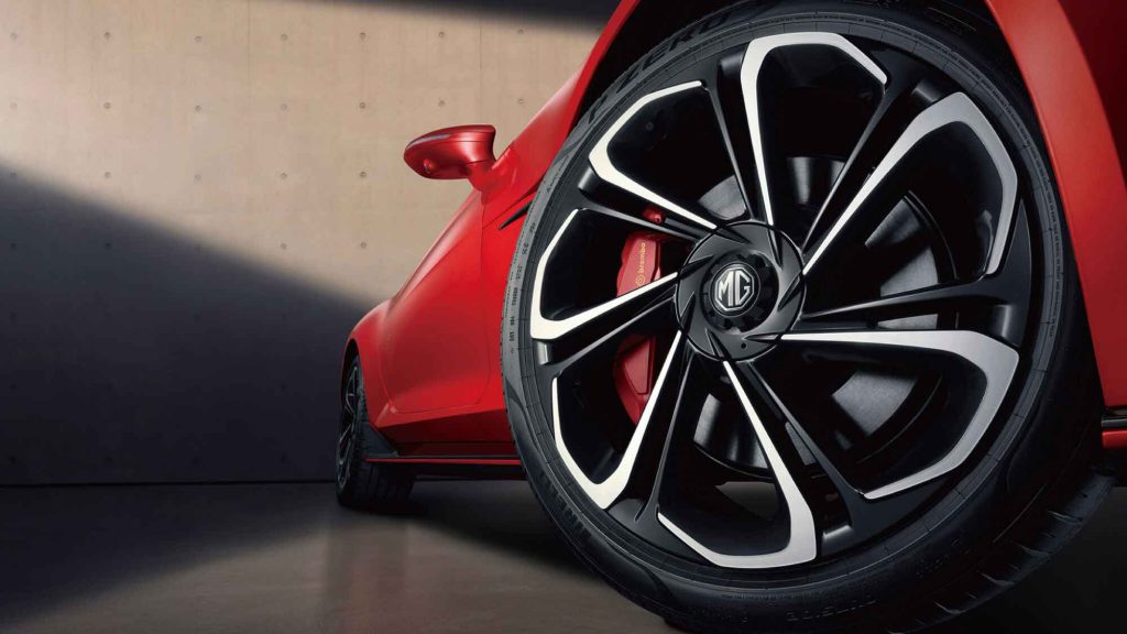 Close - up of a red MG car's wheel with a black and silver rim and red brake caliper.