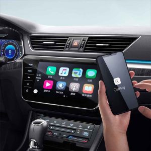 A hand holding a smartphone with CarPlay near a Škoda car's infotainment screen displaying Chinese app icons.