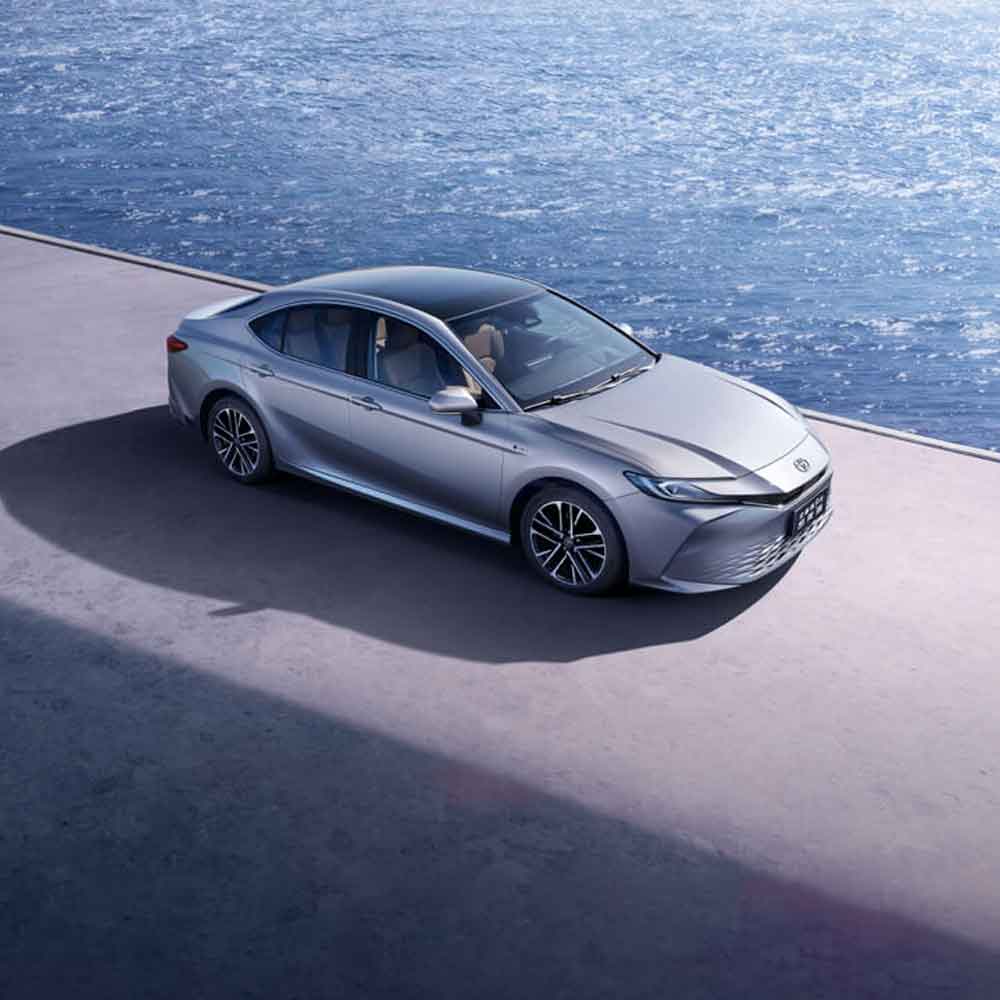 A silver sedan parked by the sea.