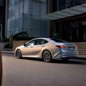 A silver Toyota Camry parked on a city street in front of a modern building.