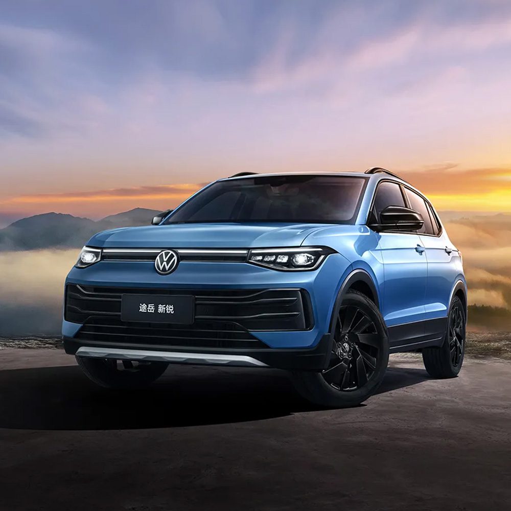 A blue Volkswagen Tharu 新锐 SUV against a sunset sky with mountains.