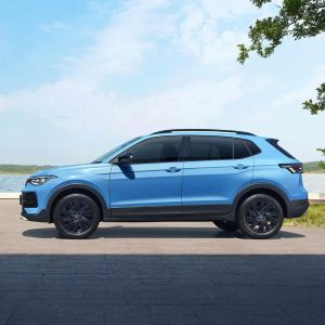 A blue Volkswagen SUV parked by a body of water under a clear sky.