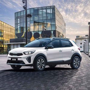 A white Kia SUV parked in front of a modern glass building.