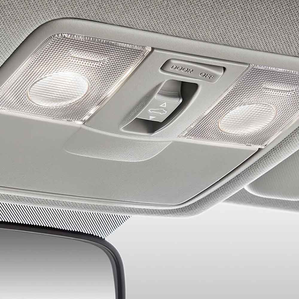 Close - up of a car's overhead console with lights and a sunroof switch.
