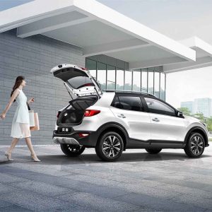 A woman with shopping bags walking towards a white Kia Stonic with an open trunk.