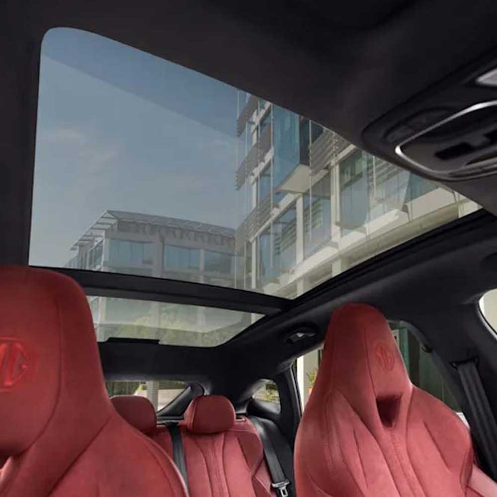 Interior of a car with red seats and a sunroof, through which a modern building is visible.
