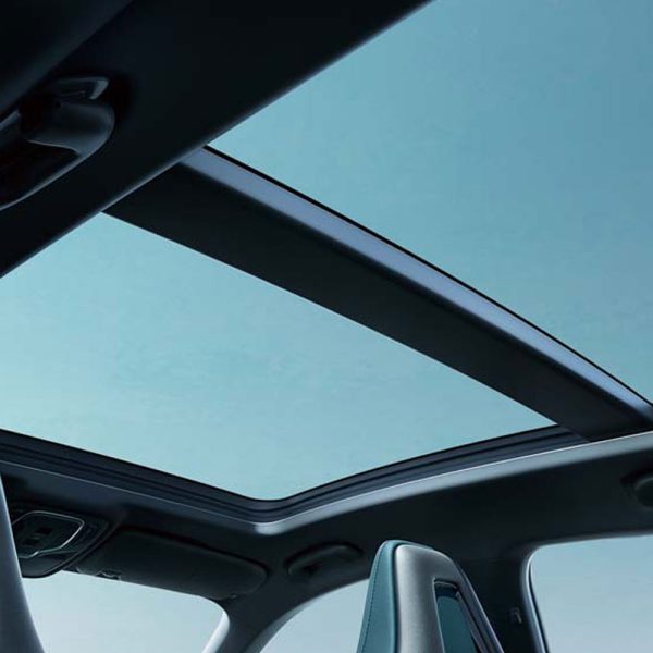View of a car's panoramic sunroof with a clear blue sky visible through it.