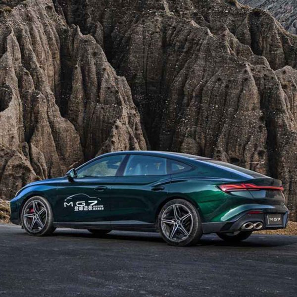 A dark green MG7 car parked on a road with rugged rock formations in the background.