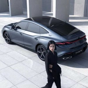 MG7 2025 1.5T 300DCT Luxury Edition product gallery image 4 A woman in black clothing walks past a silver MG7 car in a modern, open - air architectural setting.