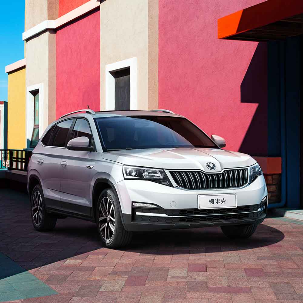 White Skoda Kamiq SUV parked in front of a colorful building.
