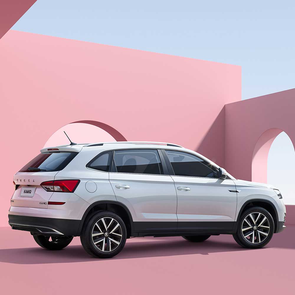 White Skoda Kamiq SUV against a pink architectural background.