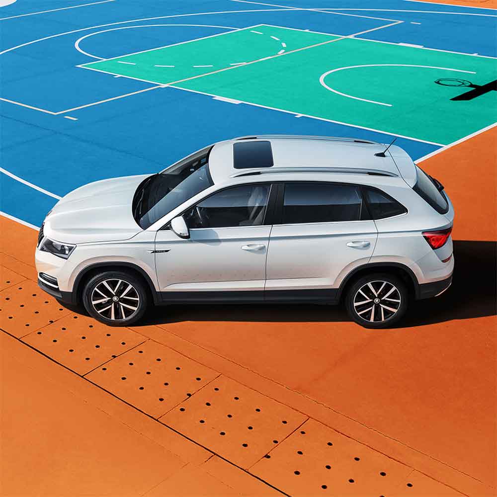 White SUV parked on a colorful sports court.
