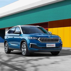 SKODA KAMIQ GT 2025 1.5L Automatic Premium Edition Hero Shot Blue Skoda Kamiq GT SUV driving past a colorful building.