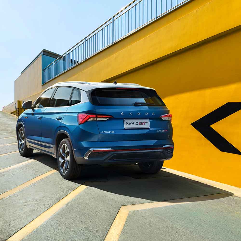 SKODA KAMIQ GT 2025 1.5L Automatic Premium Edition Rear Three-Quarter Rear view of blue Skoda Kamiq GT SUV against a yellow wall.