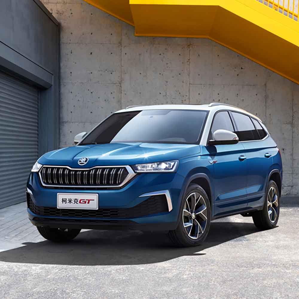 SKODA KAMIQ GT 2025 1.5L Automatic Premium Edition Three-quarter view from the left front Blue Skoda Kamiq GT SUV in front of a concrete wall with a yellow structure.