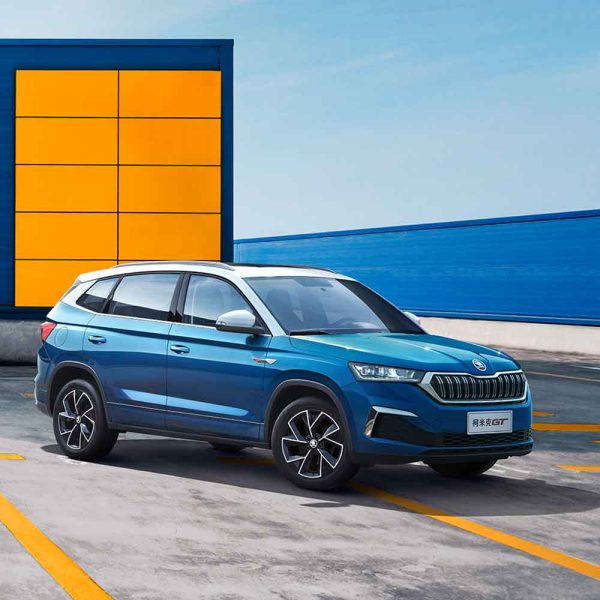 Blue Skoda Kamiq GT SUV in a parking lot with colorful background.