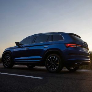 SKODA KODIAQ 2025 TSI330 5-Seater FWD Luxury Edition gallery image Profile Shot A blue SUV (Skoda Kodiaq) driving on a road at dusk.