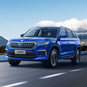 SKODA KODIAQ 2025 TSI330 5-Seater FWD Luxury Edition gallery image Rolling Shot 2 A blue Skoda Kodiaq SUV driving on a road with a clear blue sky and mountains in the background.