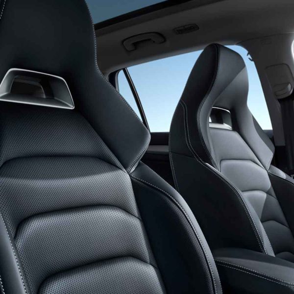 Close - up of black leather car seats with a clear blue sky visible through the car window.