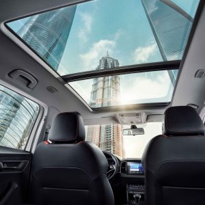 Interior of a car with a panoramic sunroof, showing tall city buildings outside.