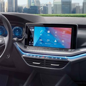 Interior of a car showing the dashboard and infotainment screen, with a cityscape in the background.