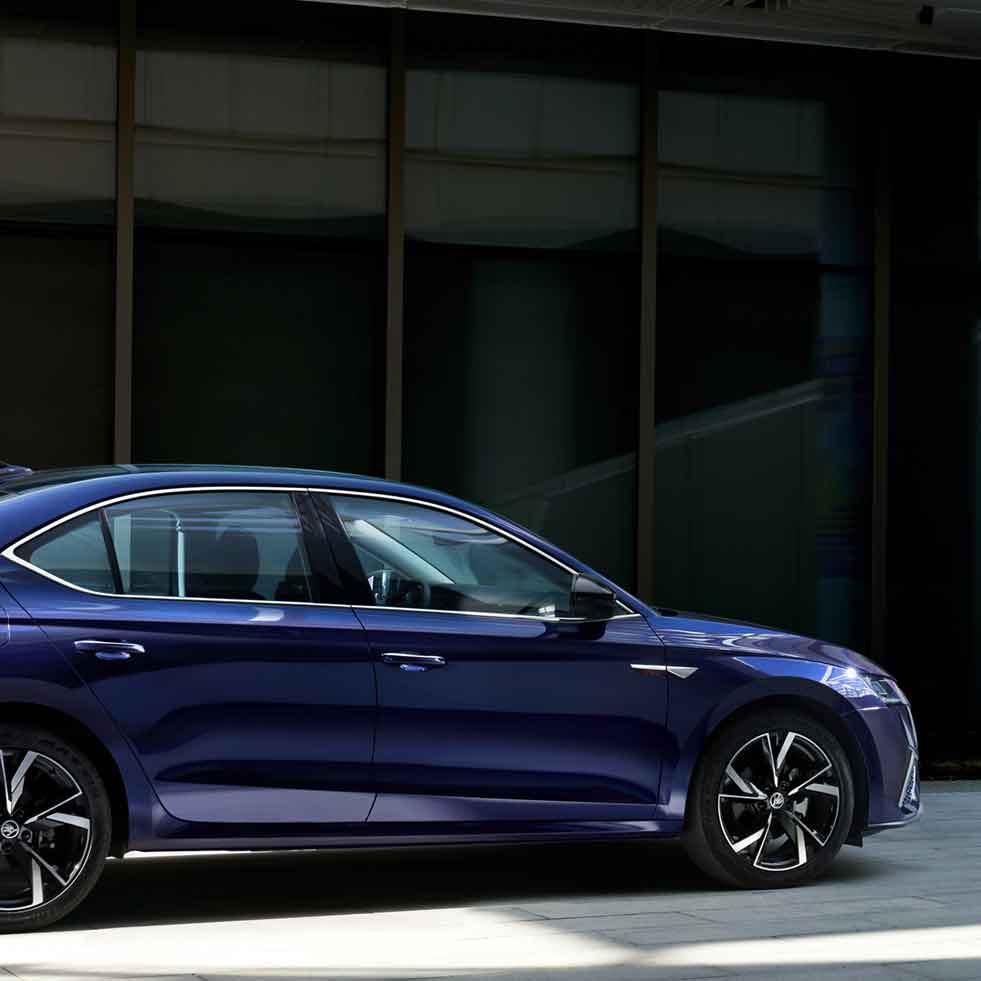 Side view of a blue sedan parked in front of a modern building.