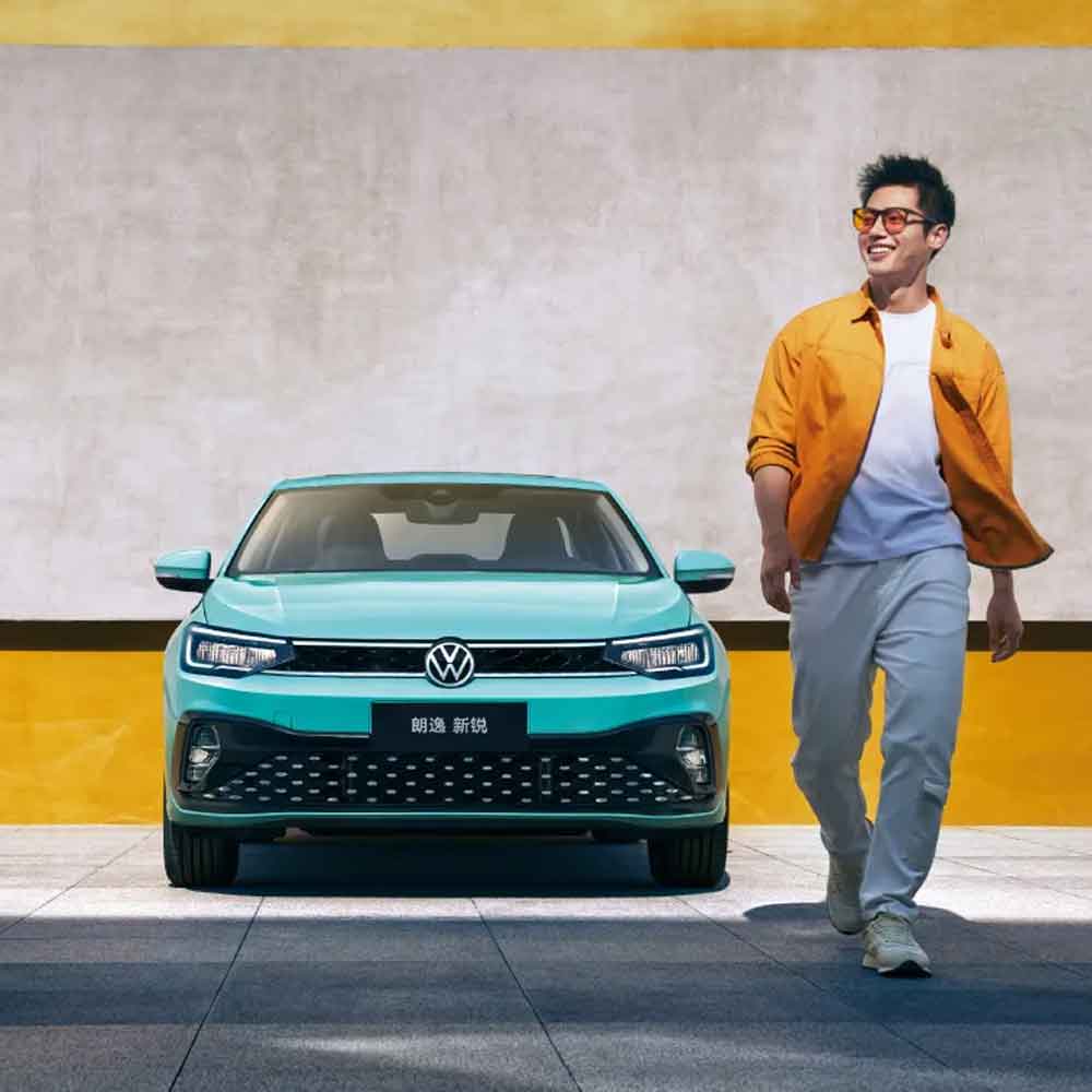 A man walking beside a turquoise Volkswagen Lavida XR sedan.