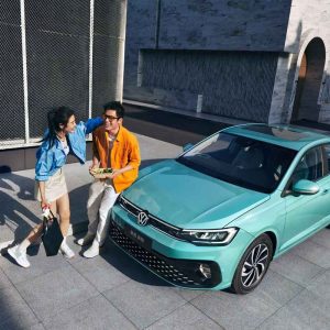 A man and a woman interacting beside a turquoise Volkswagen Lavida XR sedan.