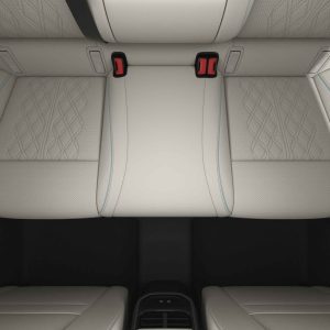 Car rear seat with beige leather upholstery and red seatbelt buckles.