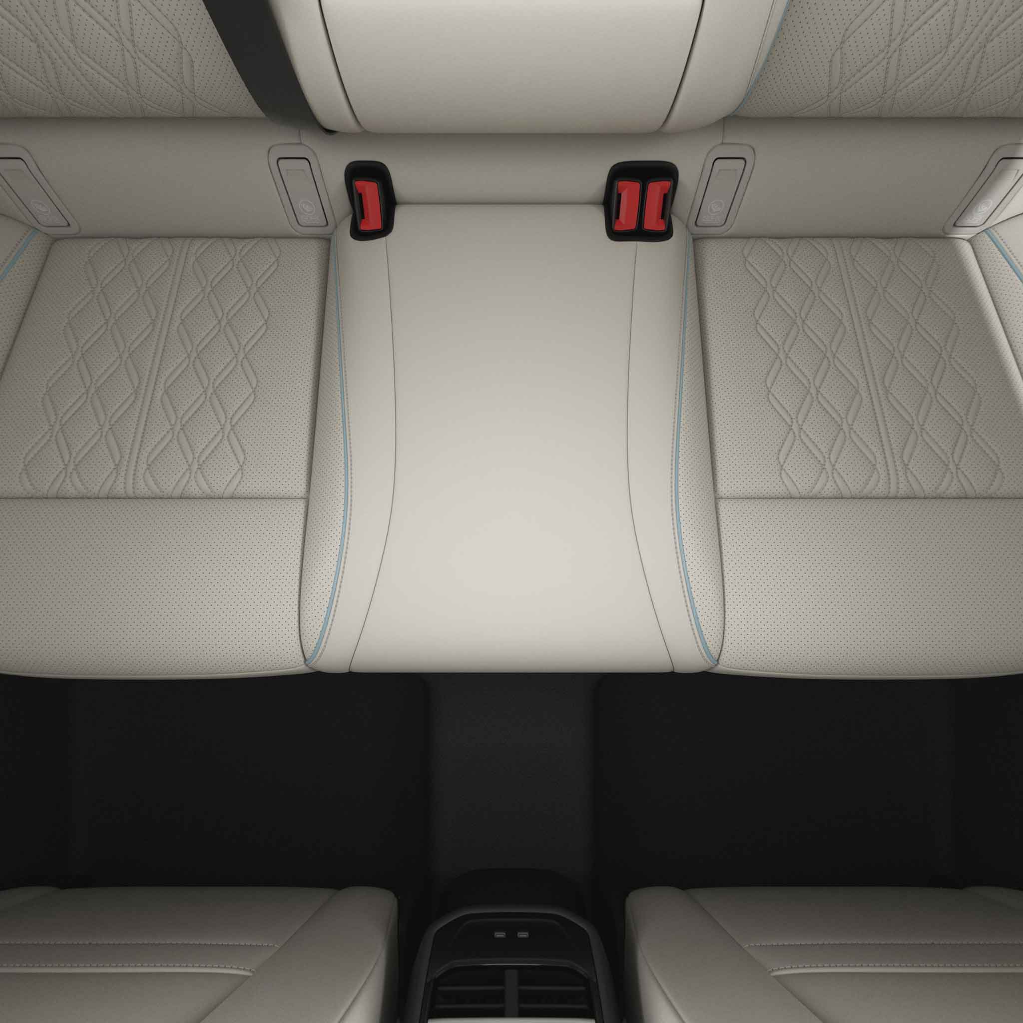 Car rear seat with beige leather upholstery and red seatbelt buckles.