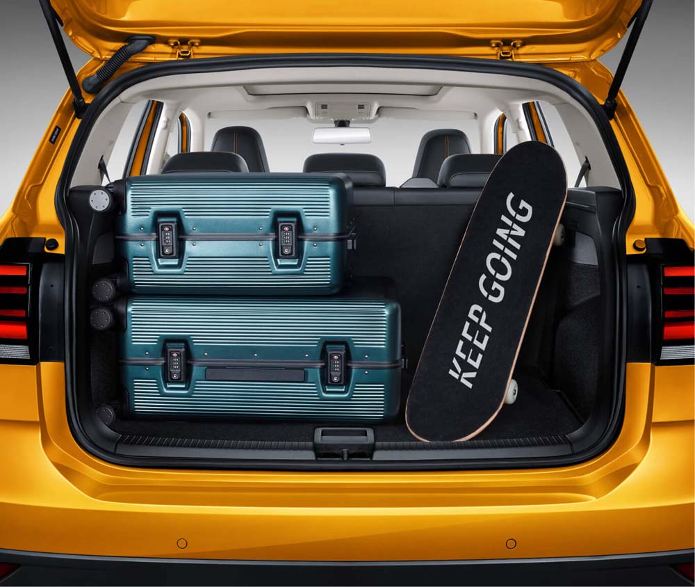 Open trunk of a yellow car with suitcases and a "KEEP GOING" skateboard inside.