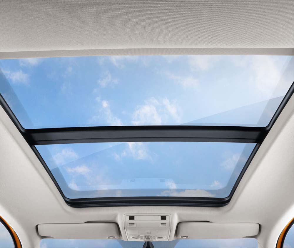 View of a car's panoramic sunroof with a blue sky and clouds visible.