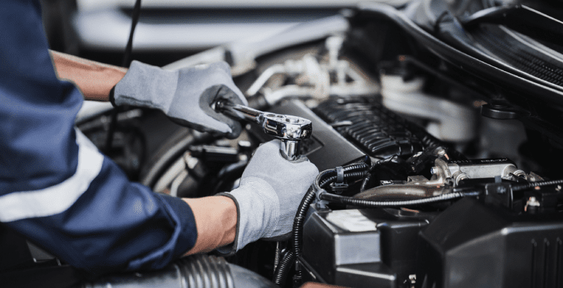 A mechanic using a ratchet wrench to repair a car engine.