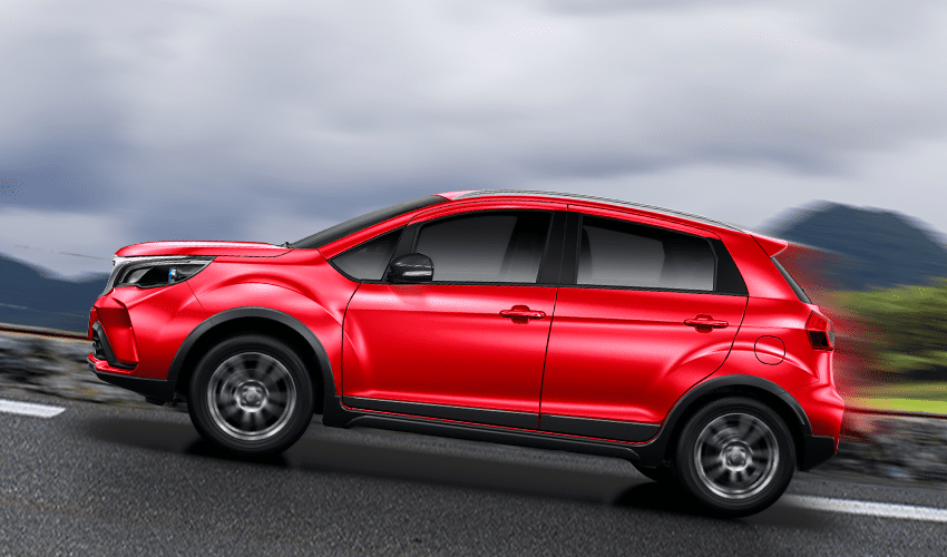 A red SUV driving on the road with a blurred mountain and sky background.