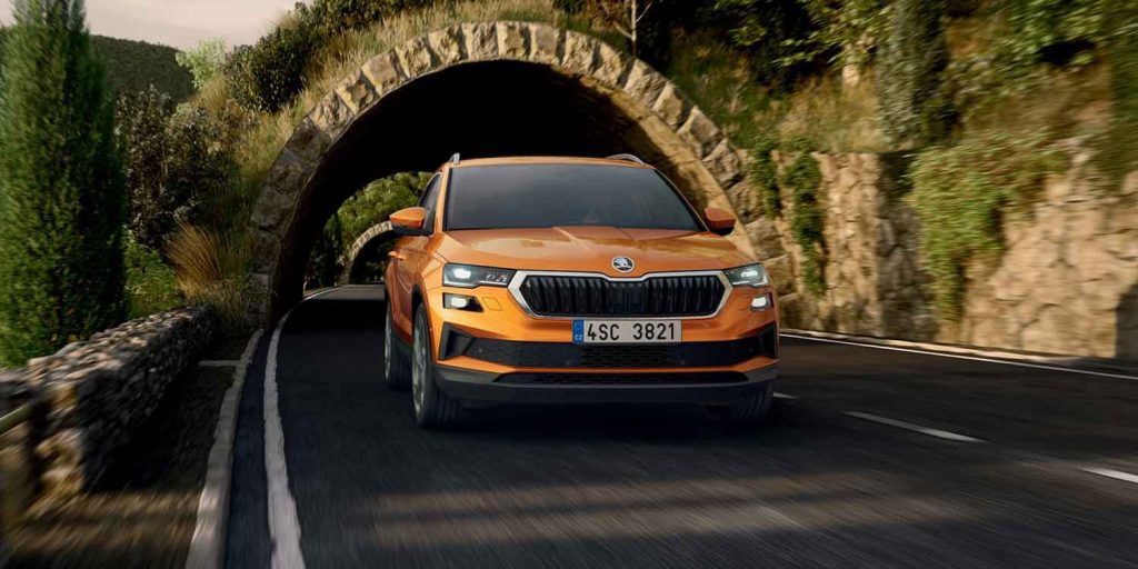 Skoda Karoq driving on the daytime countryside road, front angle, phoenix orange metallic color