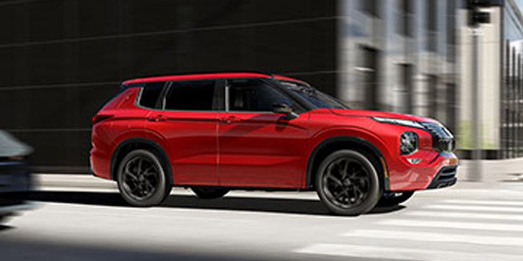 2026 Nissan Rogue PHEV side view driving on city street with buildings in the background