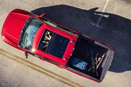 An aerial view of two people in a 2025 Ford F-150 Lightning featuring the sunroof and cargo in the truck bed