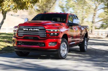 Display A red 2026 Ram 2500 Laramie traveling down a country road. The background is blurred to indicate the truck is in motion