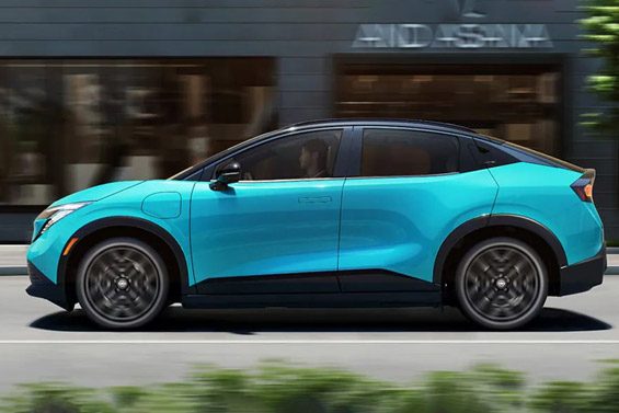 2026 Nissan LEAF in blue driving on a city street approaching an intersection