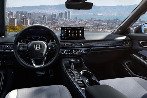 2026 Honda Civic Sedan Sport Touring Hybrid dashboard and front cabin view overlooking a city skyline