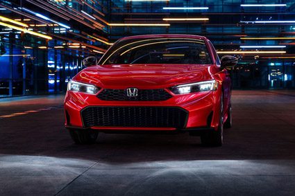2026 Honda Civic Sedan Sport Touring Hybrid in Rallye Red front view with headlights on