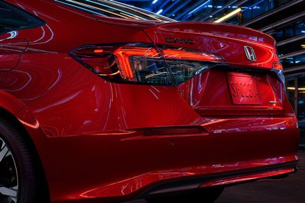 2026 Honda Civic Sedan Sport Touring Hybrid in Rallye Red rear three-quarter view showing taillight