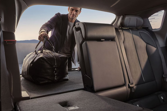 A Man Placing a Duffle Bag in the Trunk and the Right Passenger Seat Folded Down