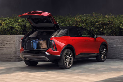 Rear View of an Orange 2026 Cadillac Optiq SUV with the Trunk Open and Things in the Trunk