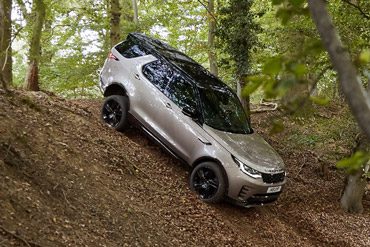 Rear view of 2026 Land Rover Discovery driving through forest road